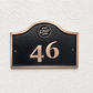 Cast bronze hotel room number sign with custom logo and raised numbers mounted on wall
