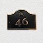 Cast bronze hotel room number sign with custom logo and raised numbers mounted on wall