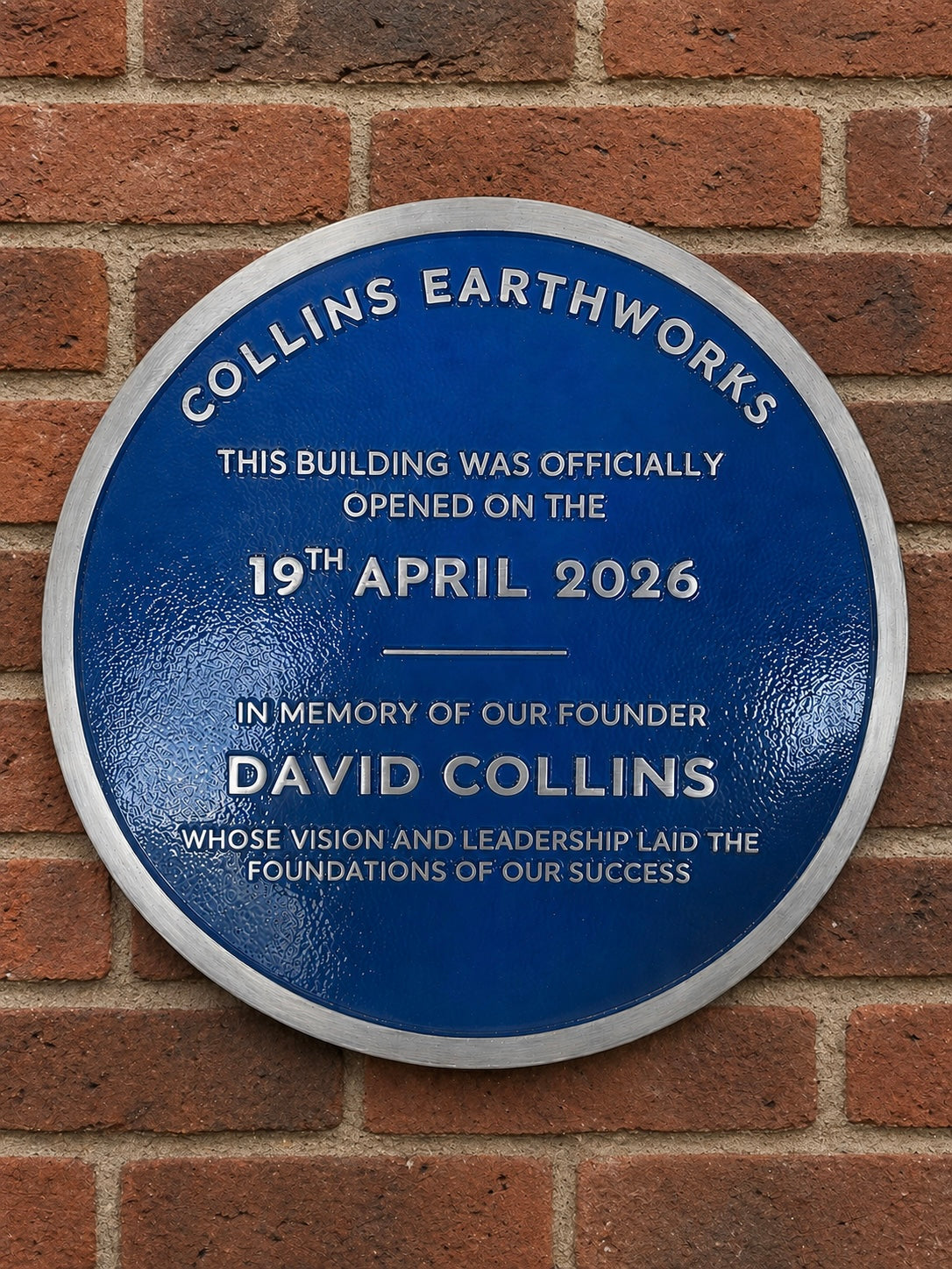Modern blue heritage plaque with brushed silver border and raised lettering mounted on exterior wall