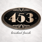 Oval bronze address plaque with raised numbers and decorative border