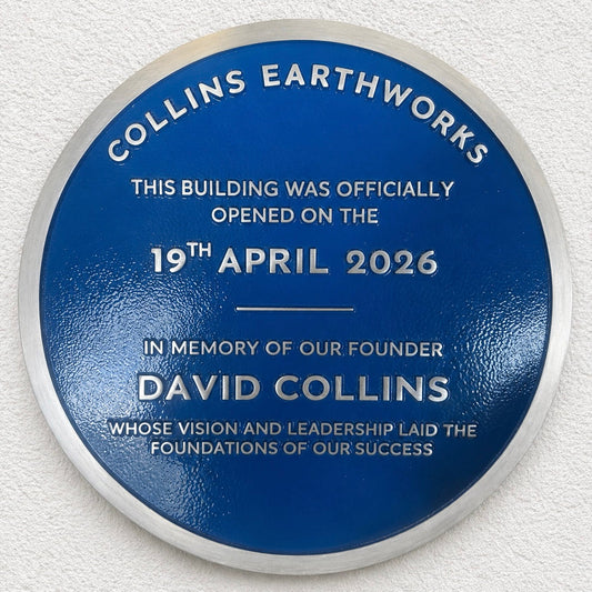 Modern blue heritage plaque with brushed silver border and raised lettering mounted on exterior wall