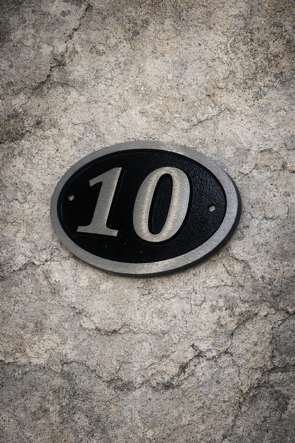 Cast aluminium oval hotel room number sign with raised numbers and black background mounted on wall