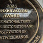 Cast bronze circular heritage plaque with raised lettering mounted on exterior wall