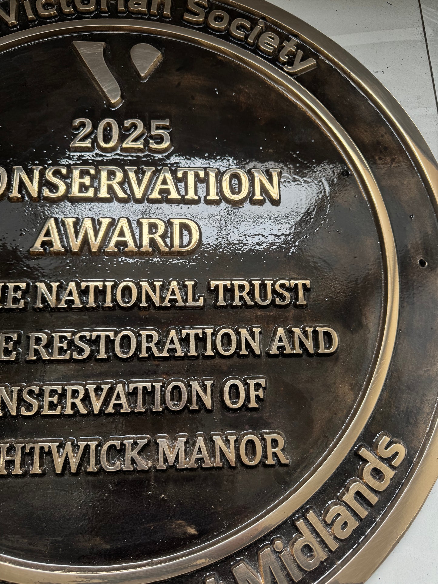 Cast bronze circular heritage plaque with raised lettering mounted on exterior wall