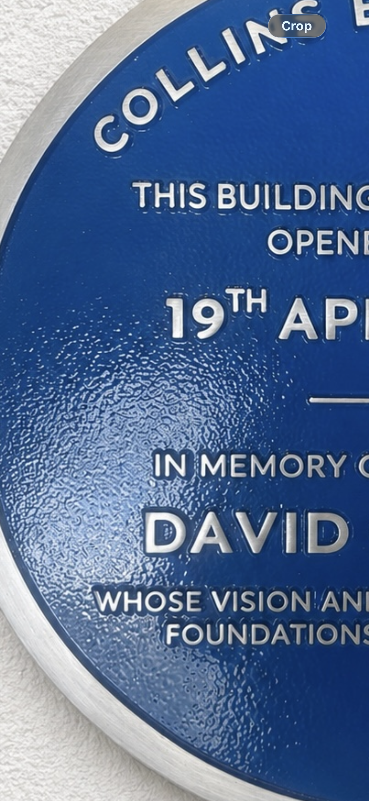 Modern blue heritage plaque with brushed silver border and raised lettering mounted on exterior wall