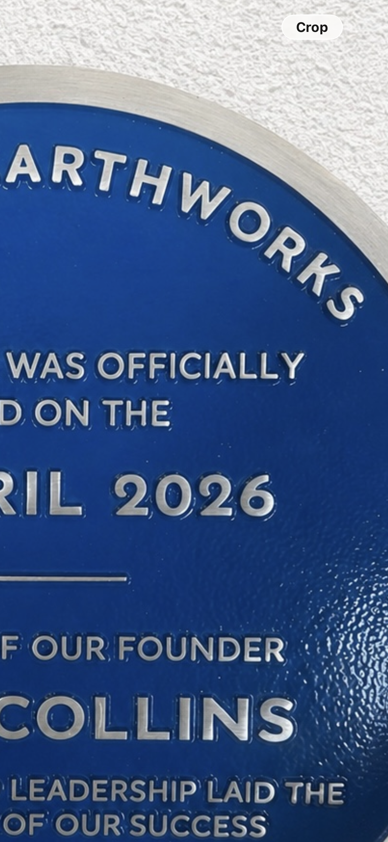 Modern blue heritage plaque with brushed silver border and raised lettering mounted on exterior wall