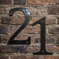 Metallic house number '21' on a brick wall