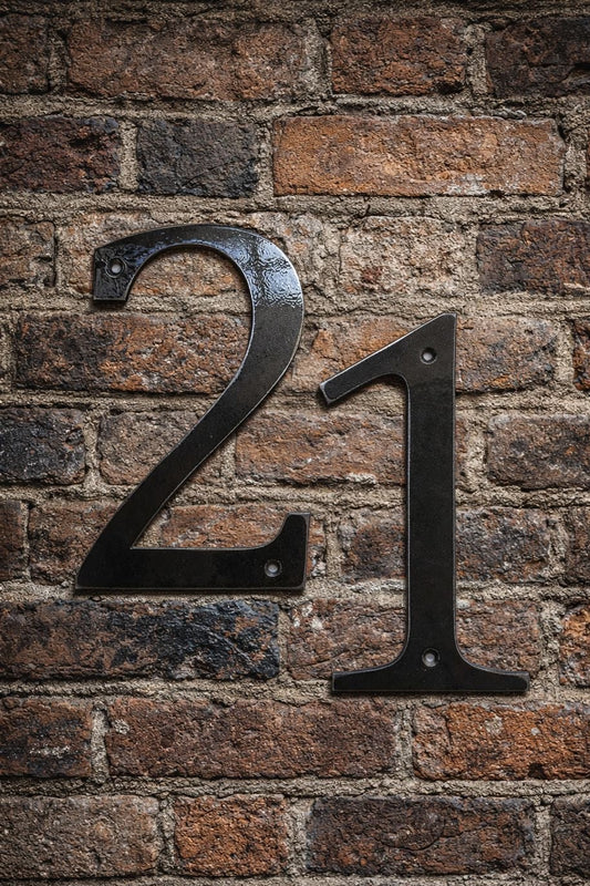 Metallic house number '21' on a brick wall