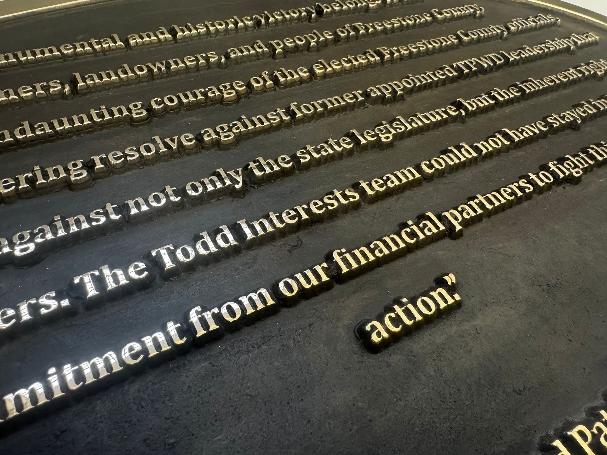 Close-up of engraved text on a black surface with gold lettering.