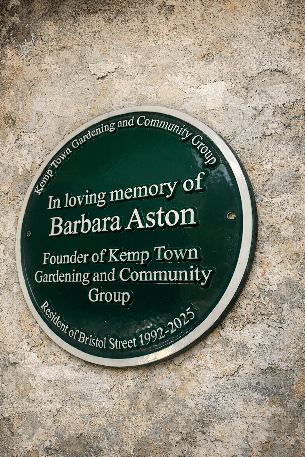 Close-up of cast aluminium green heritage plaque showing raised lettering detail
