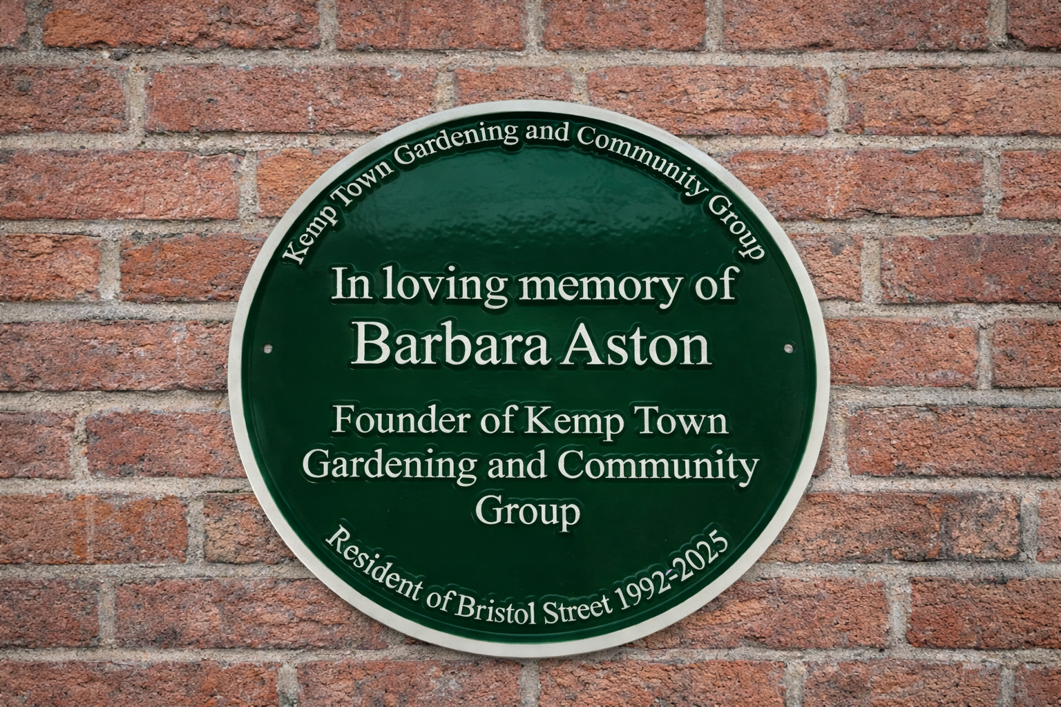 Green heritage style plaque cast in aluminium with raised lettering mounted on exterior wall