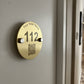 Brass door plate with 'Your Hotel Name' and number '112' on a white background