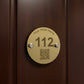 Brass hotel room number sign with QR code on a white background