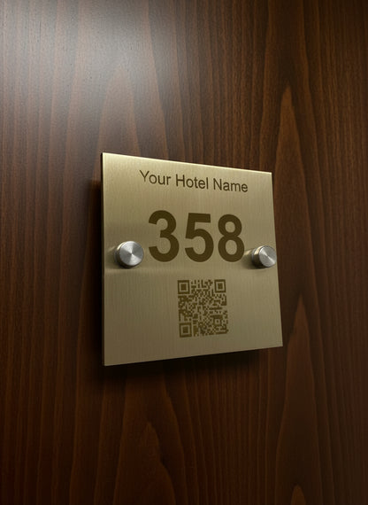 Gold hotel room number sign with QR code on a gray background